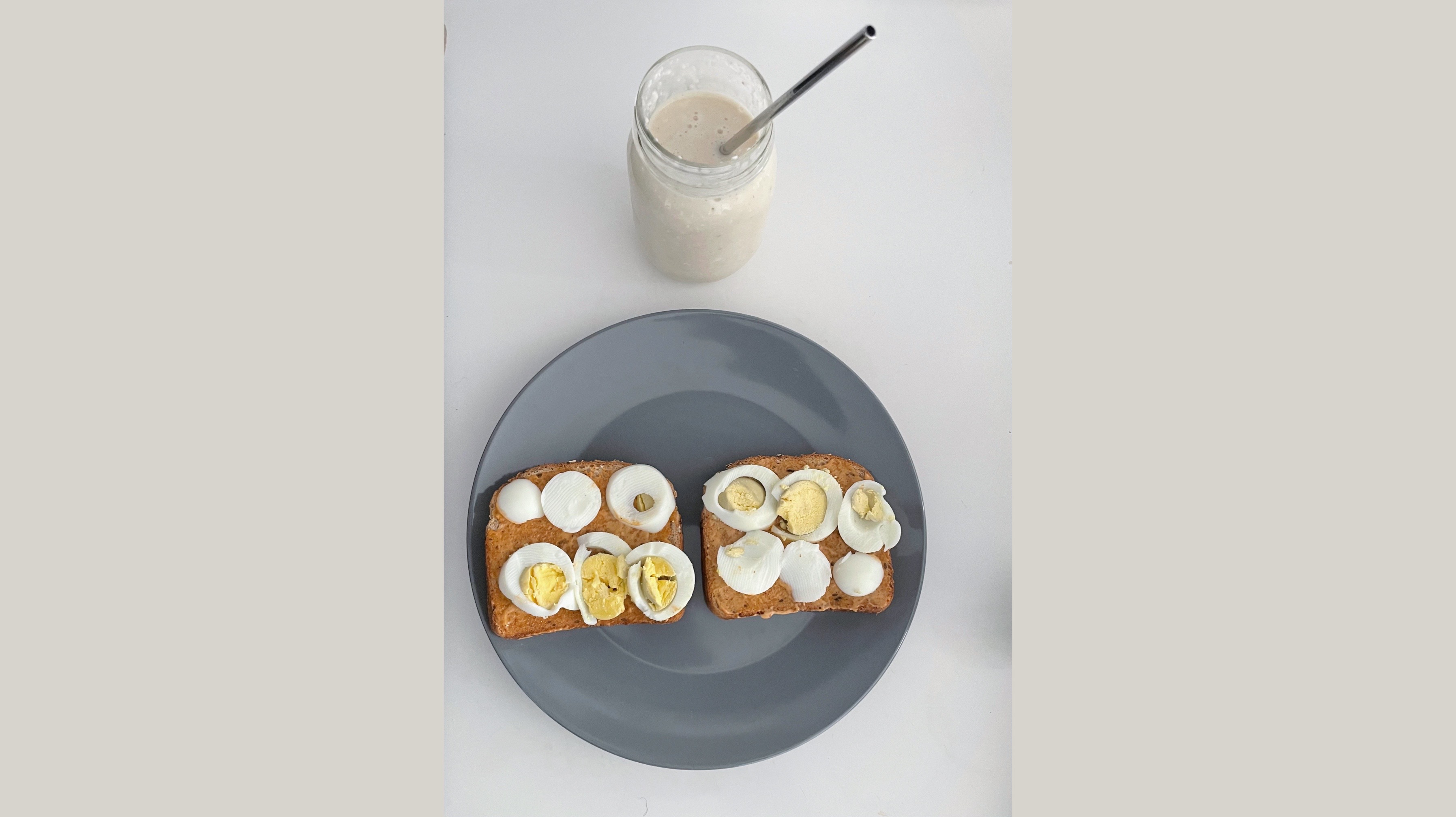 Mason jar of smoothie and a plate with bread, spread, and sliced boiled eggs